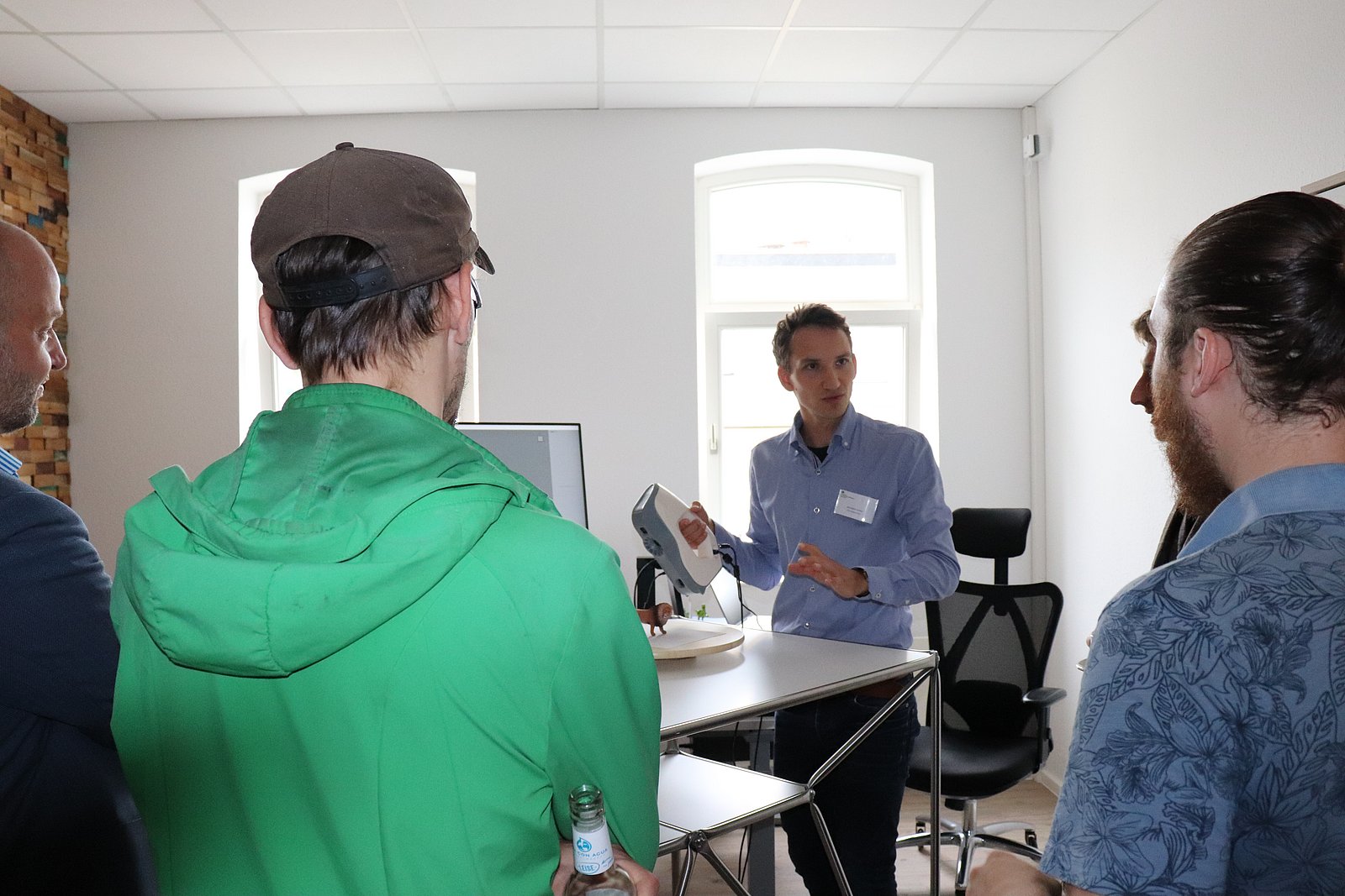 In einem Seminarraum des StartupLab zeigt ein Mitarbeiter Interessierten den 3D Handscanner. Dieser sieht einem Tischstaubsauger recht ähnlich.
