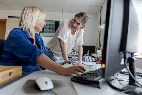 Zwei Frauen recherchieren am Computer und besprechen Ergebnisse.