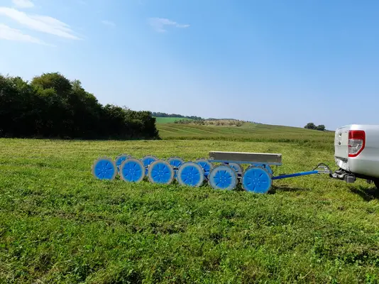 Ein Messystem wird auf einem Anhänger hinter einem Auto über das Feld gefahren.